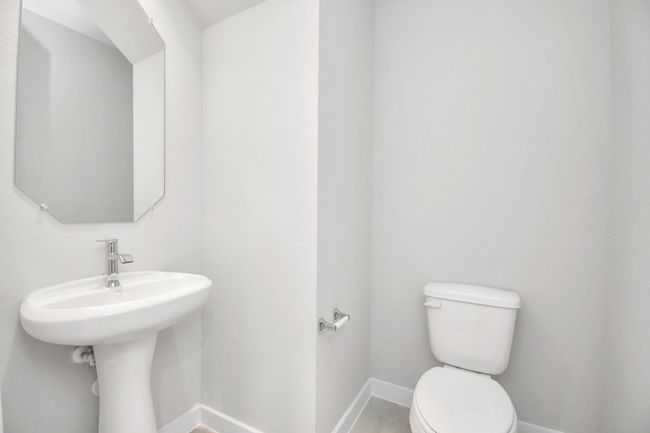 This half bathroom features a stylish pedestal sink, modern hardware, and bright recessed lighting, creating a sleek and inviting space. | Image 9