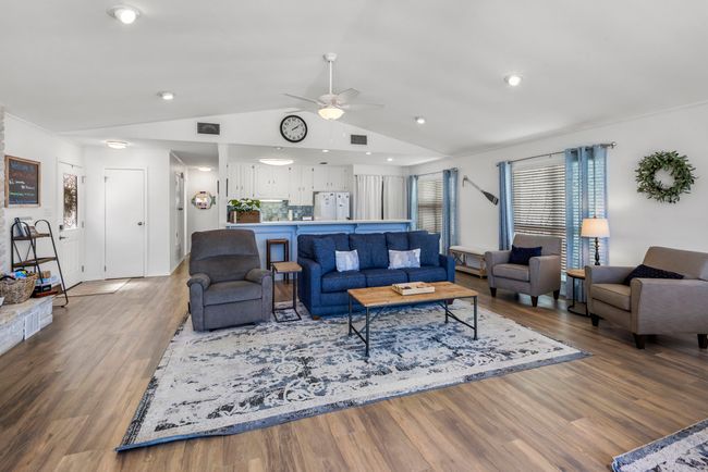 Living room with ceiling fan, visible vents, wood finished floors, and vaulted ceiling | Image 8