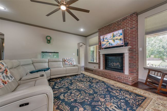 Living area featuring a ceiling fan, crown molding, healthy amount of natural light, arched walkways, and wood finished floors | Image 14