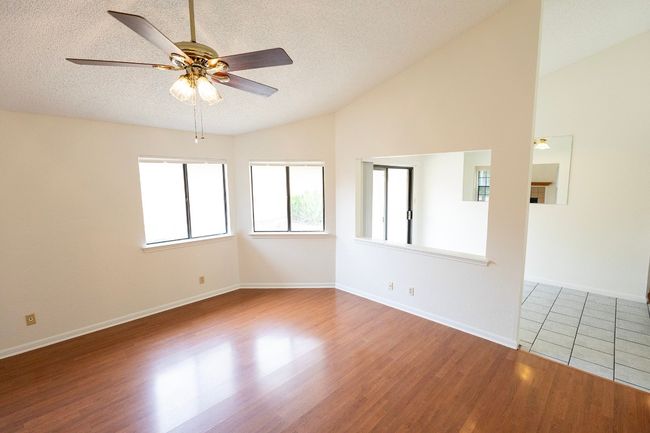 Unfurnished room with vaulted ceiling, a textured ceiling, ceiling fan, wood finished floors, and baseboards | Image 14