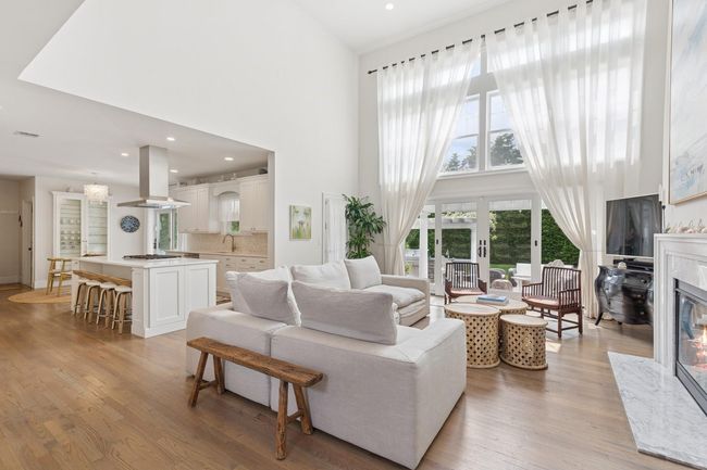 Living room with a towering ceiling, a fireplace, light wood-style floors, and recessed lighting | Image 6