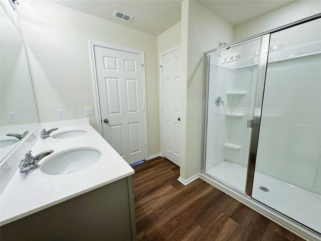 Bathroom with wood finished floors, a stall shower, double vanity, and baseboards | Image 19