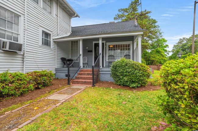 Entrance to property with cooling unit, covered porch, a yard, and a shingled roof | Image 40