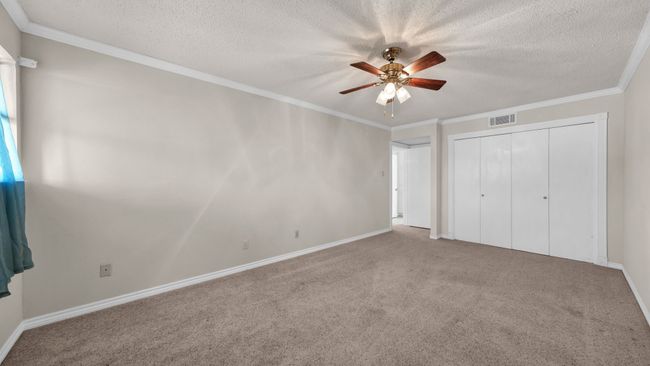 bedroom 2 featuring a closet, carpet flooring, ceiling fan, and crown molding | Image 23