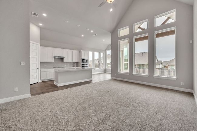 Kitchen with white cabinetry, open floor plan, light countertops, an island with sink, and dark carpet | Image 7