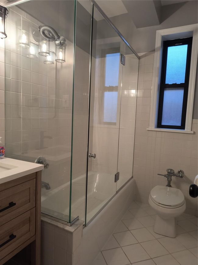 Bathroom with tile patterned flooring, tile walls, toilet, and enclosed tub / shower combo | Image 31