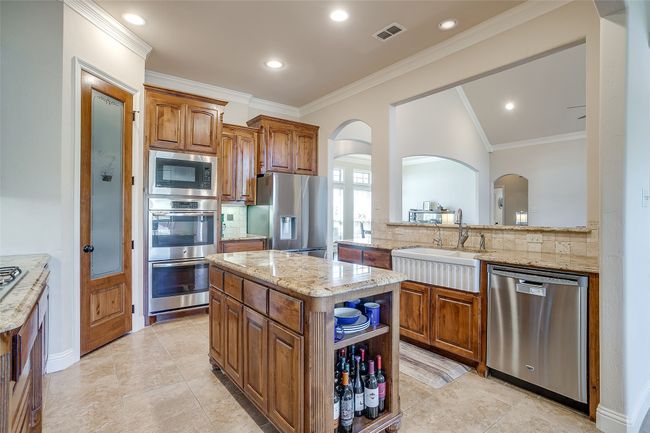Kitchen with arched walkways, visible vents, appliances with stainless steel finishes, a sink, and backsplash | Image 12