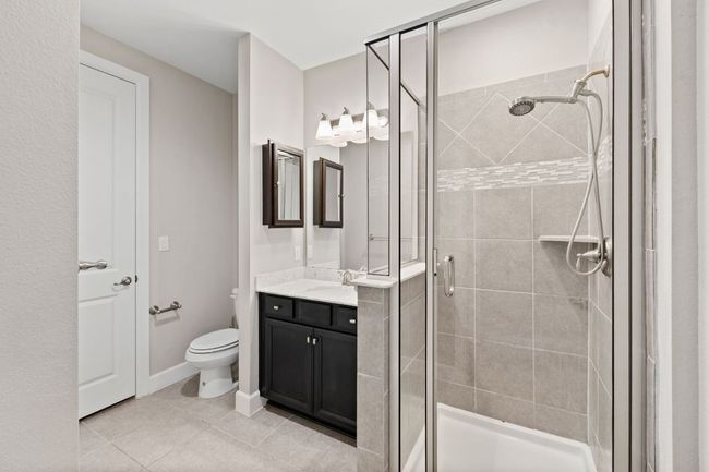 Full bathroom featuring toilet, a stall shower, tile patterned flooring, and vanity | Image 9