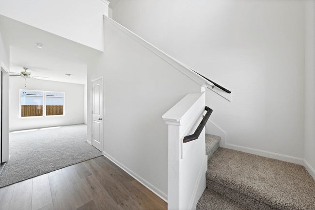 Stairs with wood finished floors, ceiling fan, baseboards, and carpet | Image 9