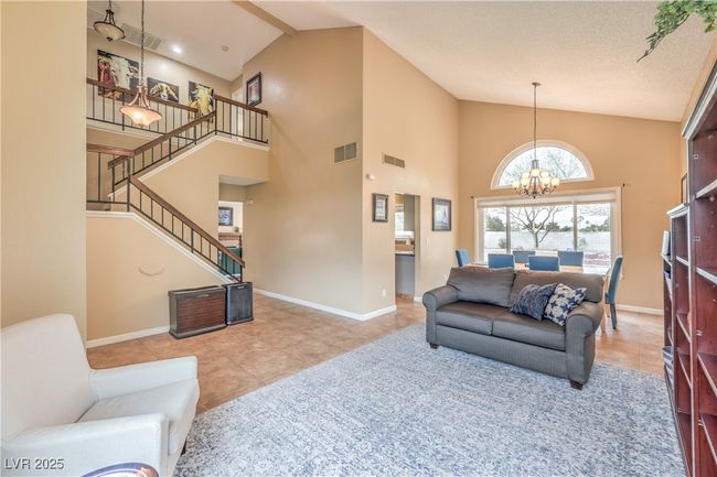 Tiled living room featuring visible baseboards, a notable chandelier, and stairway | Image 10
