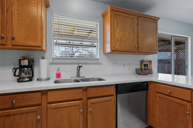 Kitchen with a sink, decorative backsplash, light countertops, and stainless steel dishwasher | Image 7