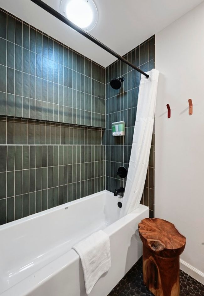 The shower/tub combo in the guest bath is lined with unqiue tile backsplash and boasts an added solar tube for additional natural light. | Image 34