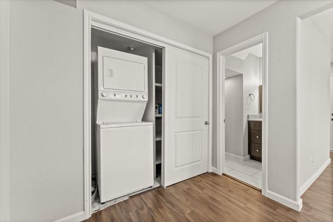 Washroom featuring estacked washer and dryer, dark wood-style floors, and a textured wall | Image 13