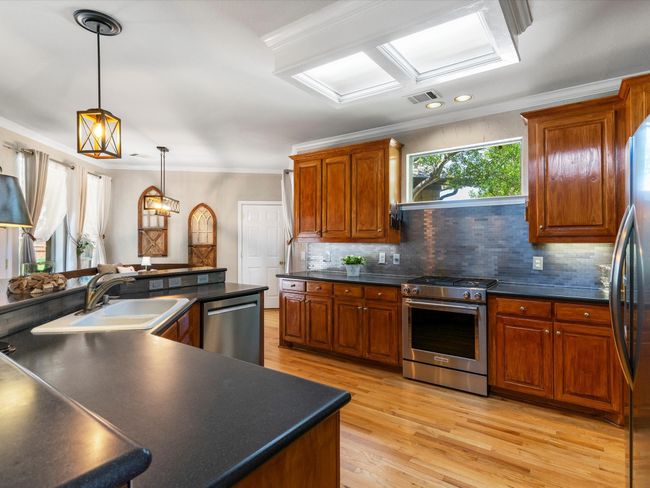 Kitchen featuring appliances with stainless steel finishes, dark countertops, exhaust hood, crown molding, and tasteful backsplash | Image 11