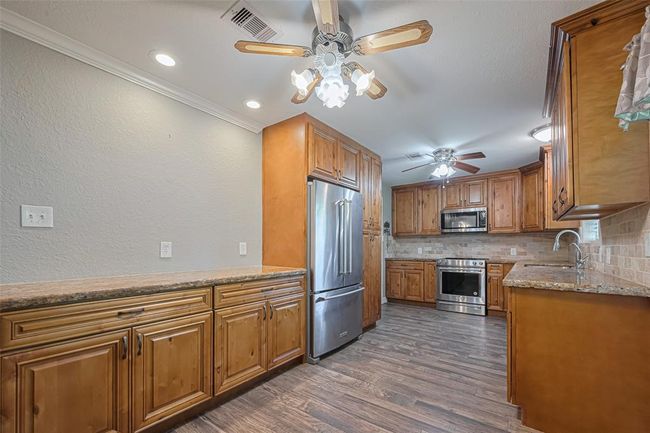 This updated kitchen features custom soft close wood cabinetry (loads of storage), stainless steel appliances, and granite countertops. It has recessed lighting, ceiling fans, and a spacious layout with a warm, inviting atmosphere. RECENT REFRIGERATOR, MICROWAVE, DISHWASHER AND STOVE !! | Image 9