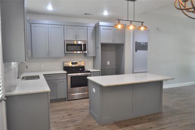 Kitchen featuring appliances with stainless steel finishes, a center island and laminate flooring. | Image 3