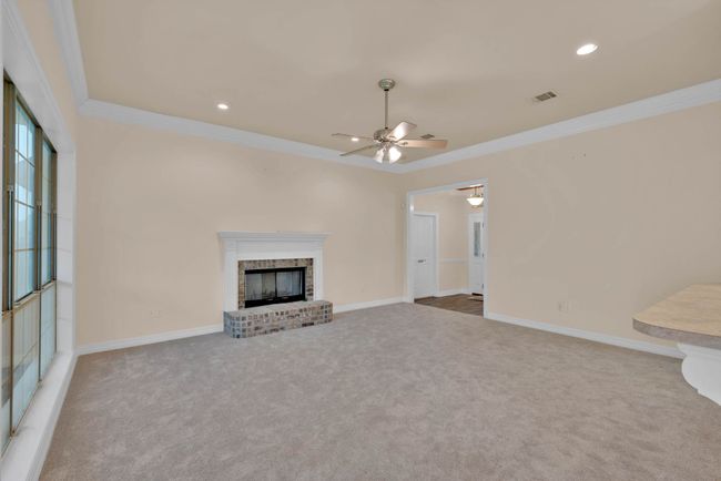 Unfurnished living room with ceiling fan, carpet flooring, ornamental molding, a fireplace, and recessed lighting | Image 6