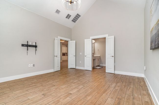 Primary bedroom with high vaulted ceiling, light wood finished floors, a chandelier, baseboards, and ensuite bathroom | Image 16