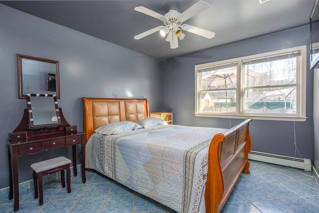 Bedroom featuring baseboard heat, tile patterned flooring and ceiling fan | Image 26