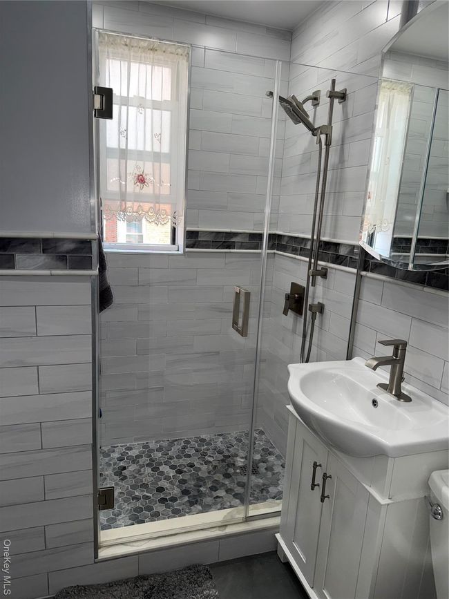 Full bath featuring a shower stall, vanity, tile walls, and tasteful backsplash | Image 4