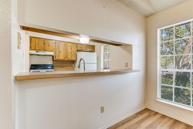 Kitchen with freestanding refrigerator, under cabinet range hood, range, light wood-style floors, and a peninsula | Image 6