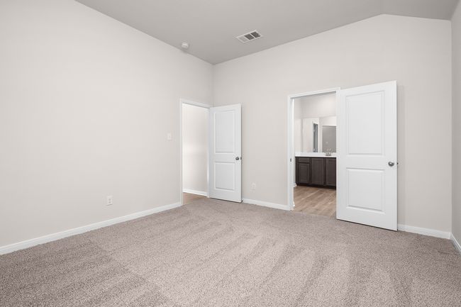 Unfurnished bedroom featuring light colored carpet, baseboards, vaulted ceiling, and connected bathroom | Image 5
