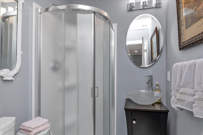 Full bathroom featuring a shower stall, vanity, visible vents, and toilet | Image 16