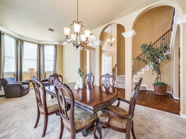 Dining space with carpet floors, a chandelier, stairway, arched walkways, and decorative columns | Image 6