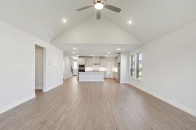 Unfurnished living room featuring light wood-type flooring, high vaulted ceiling, and ceiling fan | Image 3