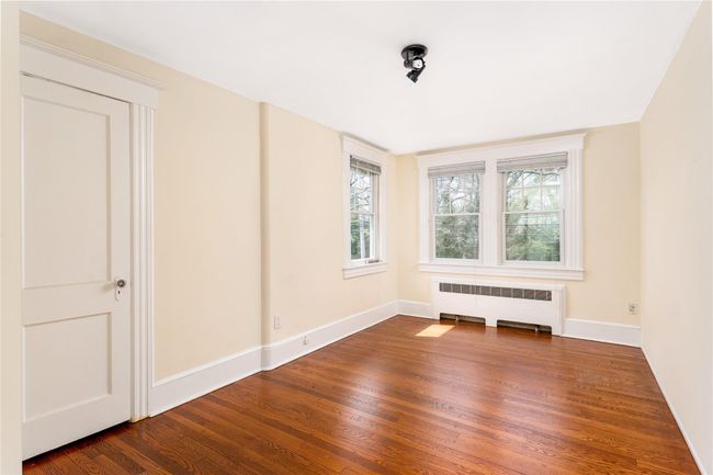 Empty room with radiator heating unit, baseboards, and dark wood finished floors | Image 12