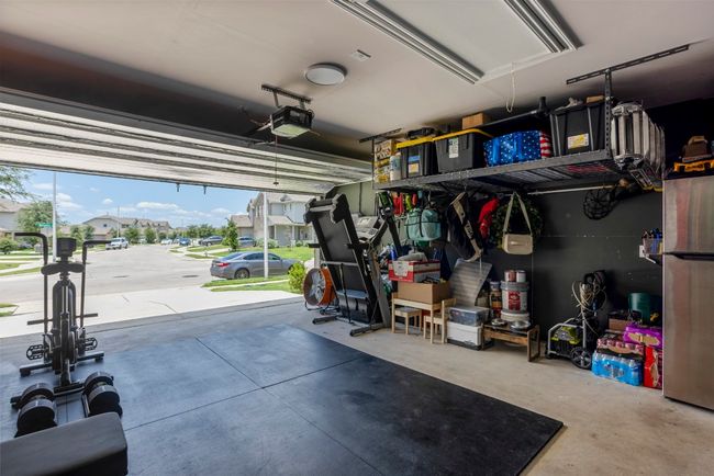 Garage featuring a garage door opener, freestanding refrigerator, and a residential view | Image 28