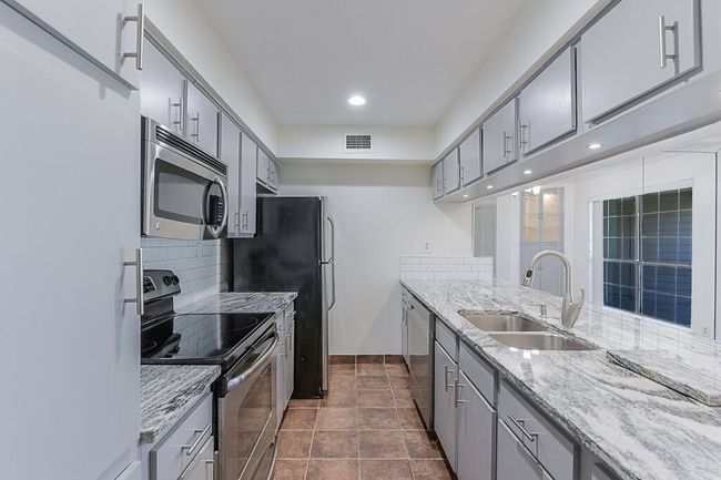 Kitchen with stainless steel appliances, visible vents, a sink, and gray cabinets | Image 5