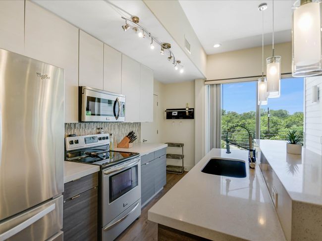 Kitchen featuring appliances with stainless steel finishes, modern cabinets, tasteful backsplash, dark wood-style flooring, and recessed lighting | Image 13