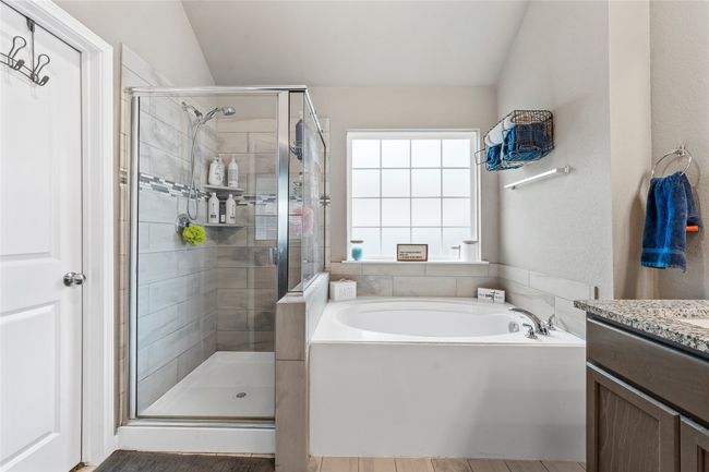 Full bath featuring a garden tub, vanity, vaulted ceiling, and a shower stall | Image 18