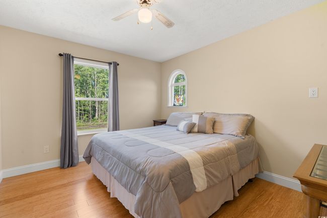 Bedroom with light wood-style flooring, baseboards, and a ceiling fan | Image 15