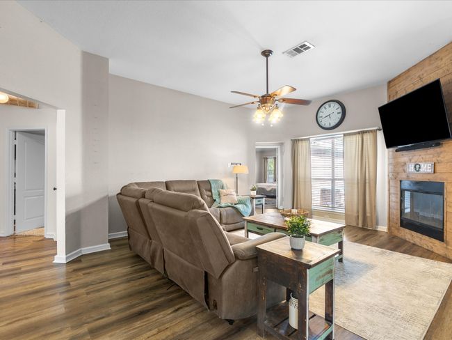 Living area featuring a ceiling fan, wood finished floors, and a fireplace | Image 14