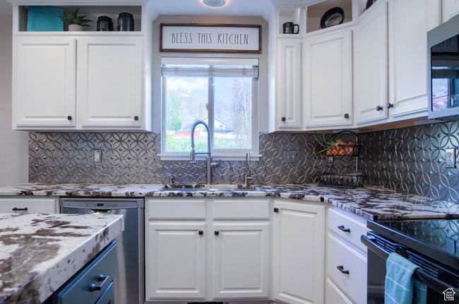 Kitchen featuring light stone counters, a sink, decorative backsplash, white cabinetry, and appliances with stainless steel finishes | Image 7