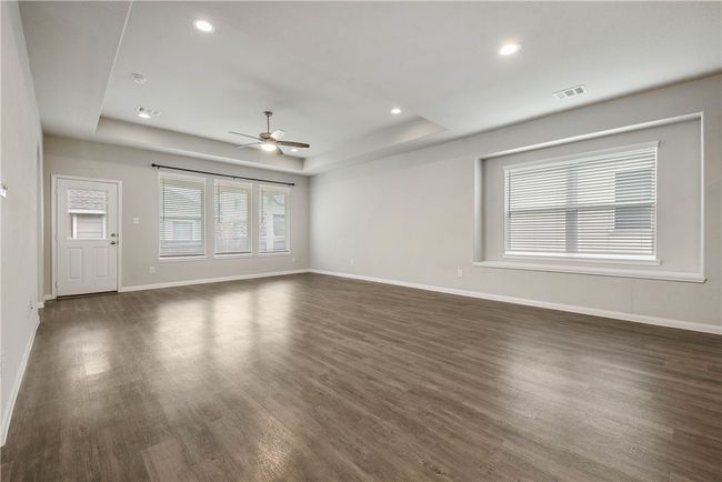 Unfurnished living room featuring a raised ceiling, a ceiling fan, dark wood-style floors, and recessed lighting | Image 8
