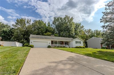 Ranch-style home with covered porch, a front yard, and a garage | Image 1