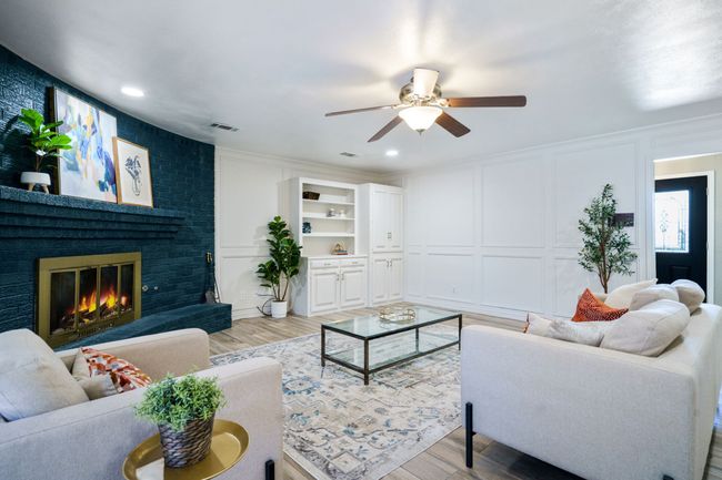 Living area with a decorative wall, a ceiling fan, light wood-style floors, a brick fireplace, and ornamental molding | Image 10