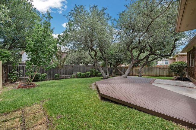 Step outside to your private backyard retreat with a covered patio, extended deck, mature trees, and lush landscaping. Unwind in the optional hot tub, perfect for Texas evenings. | Image 28