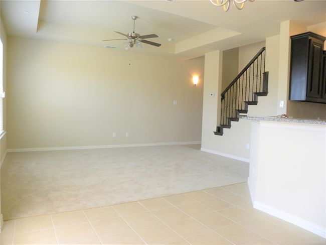 Spare room with light carpet, a tray ceiling, stairway, ceiling fan, and a chandelier | Image 14