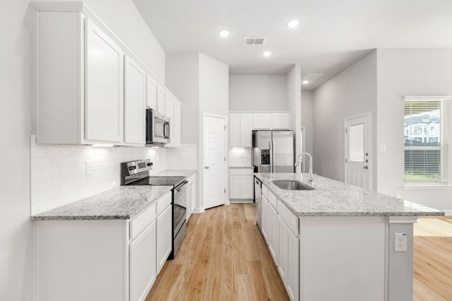 Kitchen featuring visible vents, decorative backsplash, appliances with stainless steel finishes, light wood-type flooring, and a sink | Image 13