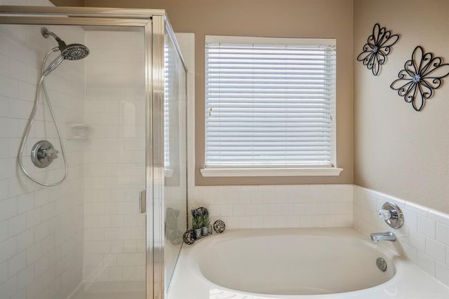 A closer view of the primary bath shows the soaking tub beneath a window, offering natural light, alongside the separate shower, creating a functional and well-appointed space. | Image 20