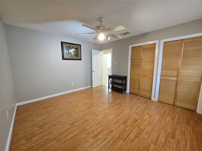 Unfurnished bedroom with two closets, light wood-style floors, and a ceiling fan | Image 16