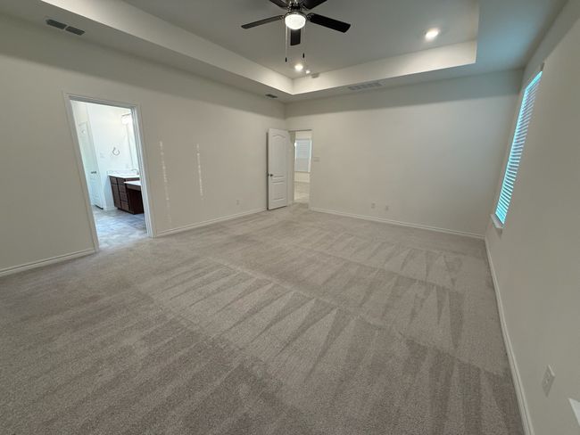 Empty room with a tray ceiling, light colored carpet, a ceiling fan, baseboards, and recessed lighting | Image 12