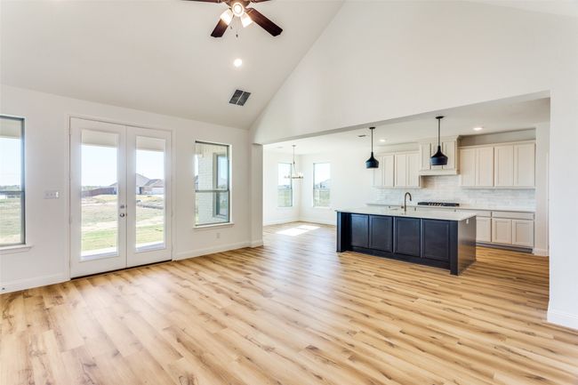 Kitchen featuring light hardwood / wood-style floors, tasteful backsplash, a kitchen island with sink, high vaulted ceiling, and pendant lighting | Image 8