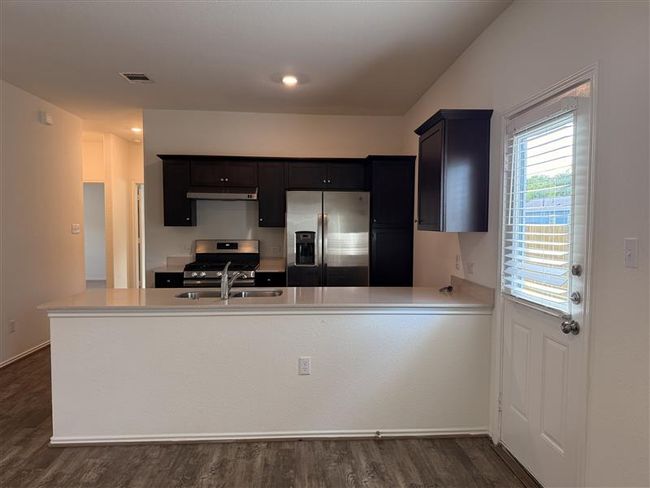 Kitchen with appliances with stainless steel finishes, light countertops, a sink, dark wood-style floors, and under cabinet range hood | Image 6