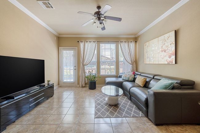 Living room with crown molding, a ceiling fan, visible vents, and a healthy amount of sunlight | Image 20
