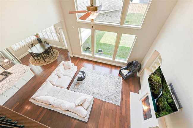 Stunning bird’s-eye view of the open-concept living and dining space, showcasing soaring ceilings, expansive windows, and warm hardwood flooring. The layout offers an ideal blend of natural light, flow, and functionality for everyday living and entertaining. | Image 21